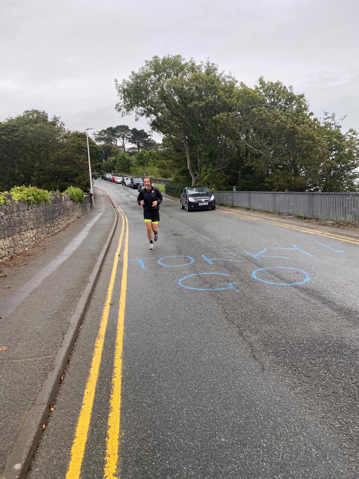 Chris running down a hill with "Go Torky" written in chalk in big letters on the road