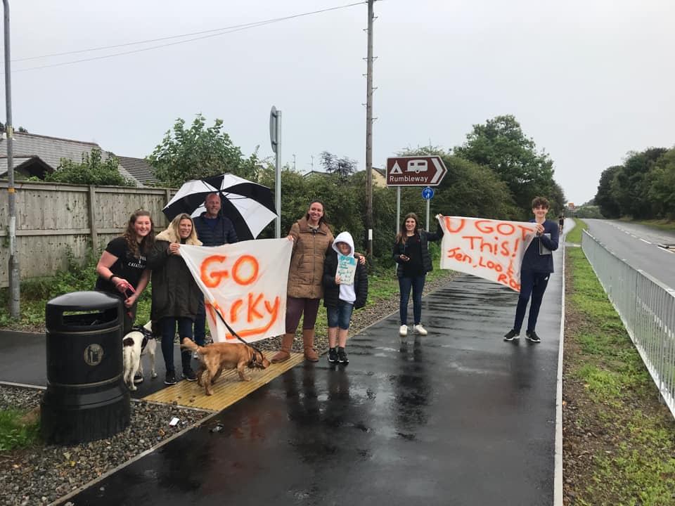A group of people holding banners reading "Go Torky" and "You got this" stood in the rain at the side of a road